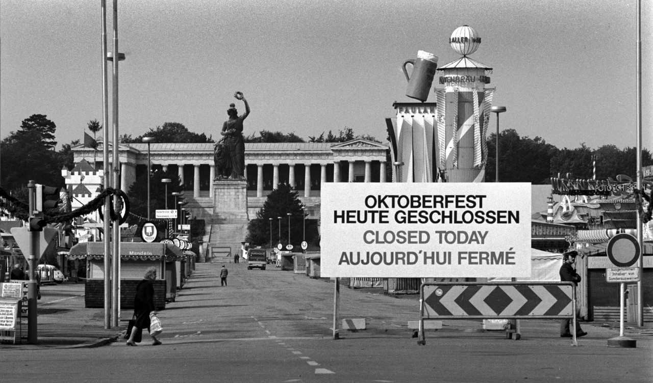 


                 Leere Theresienwiese mit den aufgebauten Zelten des Oktoberfests und der Bavaria Statue im Hintergrund und großem Geschlossen-Schild im Vordergrund.